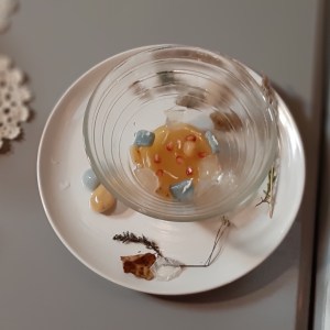 Kuvassa on lasikulho, jossa on japanilaisen emäntämme valmistamia mykyjä. Ne ovat hyvin pieniä. Lasikulhon alla on lautanen, jolla on myös muutamia mykyjä.